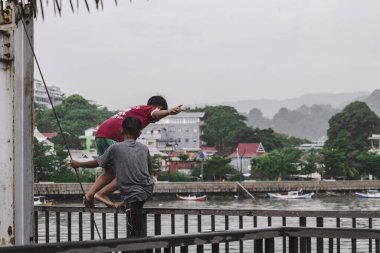 Labuan Bajo, Endonezya 'nın rıhtımında oynayan iki çocuk. Biri denize atlamaya hazırlanırken diğeri bir ipe tutundu.