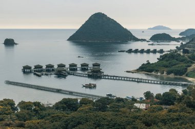 Endonezya 'nın Labuan Bajo kasabası Komodo' da su üzerinde kulübeleri olan tepelerin ve körfezin havadan görüntüsü.