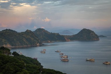Endonezya 'nın Labuan Bajo kasabası Komodo' da su üzerinde kulübeleri olan tepelerin ve körfezin havadan görüntüsü.