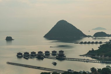 Endonezya 'nın Labuan Bajo kasabası Komodo' da su üzerinde kulübeleri olan tepelerin ve körfezin havadan görüntüsü.