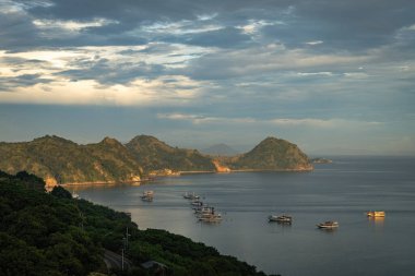 Endonezya 'nın Labuan Bajo kasabası Komodo' da su üzerinde kulübeleri olan tepelerin ve körfezin havadan görüntüsü.