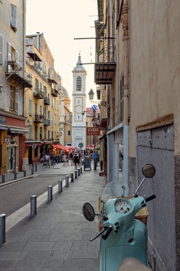 Nica 'daki yaya sokağı eski model scooter' ı kaldırıma park etmiş insanlar arka planda tarihi evlerle sokakta yürüyor Fransa 'da.