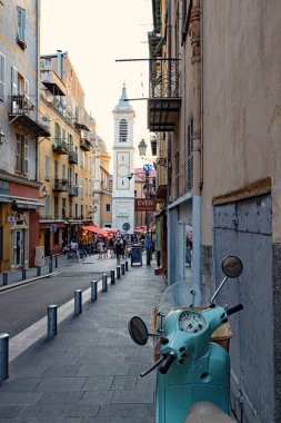 Nica 'daki yaya sokağı eski model scooter' ı kaldırıma park etmiş insanlar arka planda tarihi evlerle sokakta yürüyor Fransa 'da.