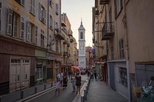 Nica 'daki yaya sokağı eski model scooter' ı kaldırıma park etmiş insanlar arka planda tarihi evlerle sokakta yürüyor Fransa 'da.