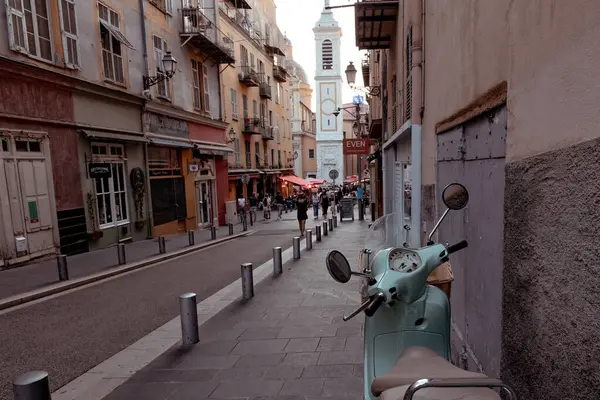 Nica 'daki yaya sokağı eski model scooter' ı kaldırıma park etmiş insanlar arka planda tarihi evlerle sokakta yürüyor Fransa 'da.