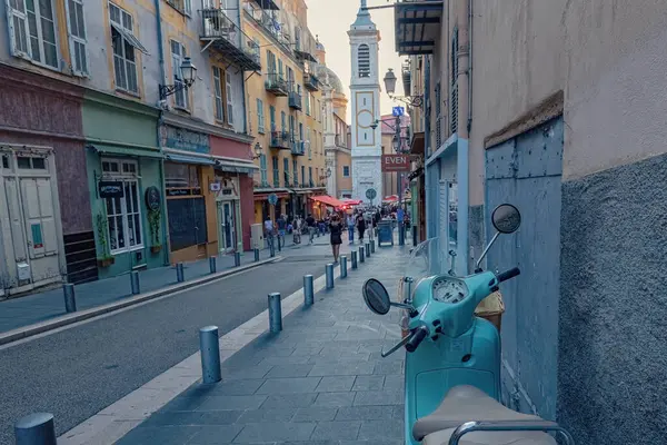 Nica 'daki yaya sokağı eski model scooter' ı kaldırıma park etmiş insanlar arka planda tarihi evlerle sokakta yürüyor Fransa 'da.