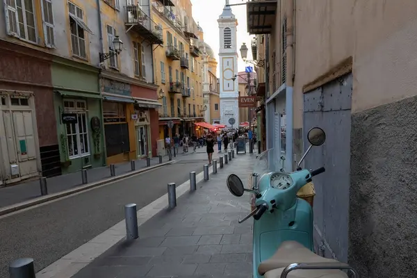 Nica 'daki yaya sokağı eski model scooter' ı kaldırıma park etmiş insanlar arka planda tarihi evlerle sokakta yürüyor Fransa 'da.