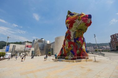 BILBAO, SPAIN - 3 Temmuz 2024: Çiçeklerle kaplı köpek yavrusu heykeli, İspanya 'nın Bilbao kentindeki Guggenheim Müzesi' nin dışında bir sanat eseri