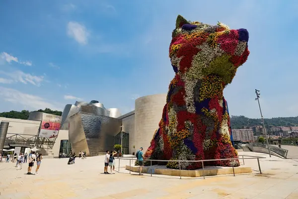 BILBAO, SPAIN - 3 Temmuz 2024: Çiçeklerle kaplı köpek yavrusu heykeli, İspanya 'nın Bilbao kentindeki Guggenheim Müzesi' nin dışında bir sanat eseri