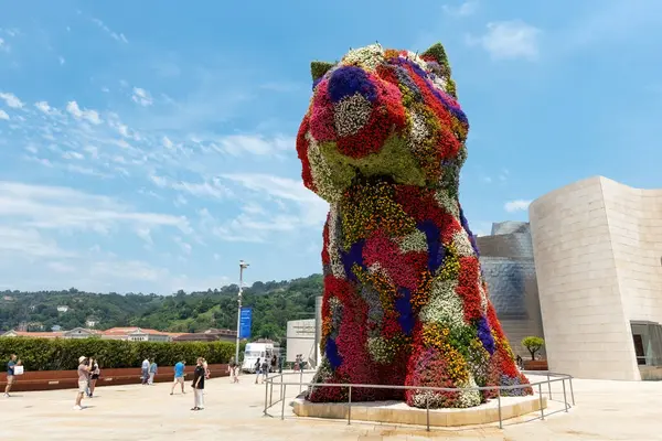 BILBAO, SPAIN - 3 Temmuz 2024: Çiçeklerle kaplı köpek yavrusu heykeli, İspanya 'nın Bilbao kentindeki Guggenheim Müzesi' nin dışında bir sanat eseri