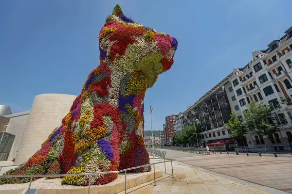 BILBAO, SPAIN - 3 Temmuz 2024: Çiçeklerle kaplı köpek yavrusu heykeli, İspanya 'nın Bilbao kentindeki Guggenheim Müzesi' nin dışında bir sanat eseri