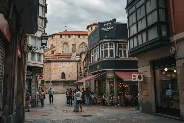 BILBAO, SPAIN - 20 Temmuz 2024: Casco Viejo, Bilbao 's Old Town' da sokak manzarası, arka planda tarihi San Antn Kilisesi ve yerel halk canlı kafe kültürünün tadını çıkarıyor