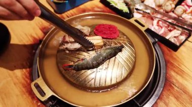 Top view of the traditional asian grill or hot pot in Thail restaurant cooking seafood and meat