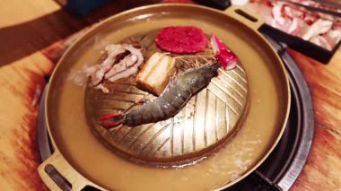 Tayland restoranındaki geleneksel Asya ızgarasının ya da sıcak tenceresinin deniz mahsulleri ve et pişirme manzarası