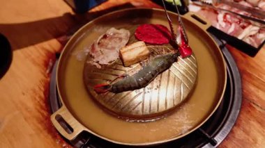 Tayland restoranındaki geleneksel Asya ızgarasının ya da sıcak tenceresinin deniz mahsulleri ve et pişirme manzarası