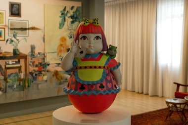KUALA LUMPUR, MALAYSIA - 20 Ocak 2025: Modern bir sanat galerisinde sergilenen, omzunda küçük bir hayvan olan oyuncak bebek benzeri bir oyun kartının renkli çağdaş heykeli