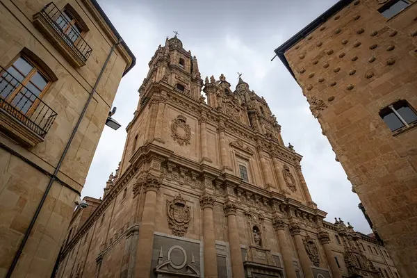 SALAMANCA, İspanya - 3 Temmuz 2024: Clereca Kilisesi 'nin Barok kuleleri, İspanya' nın Salamanca kentindeki ikonik Casa de las Conchas 'ın yanında yükseliyor.