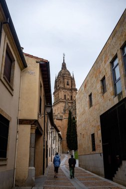 SALAMANCA, SPAIN - 3 Temmuz 2024: Salamanca İspanya 'da eski bir kasaba caddesi İglesia La Clereca Katolik Kilisesi' nin Salamanca 'daki kulelerinin manzarası ile kasabada yürüyen insanlar