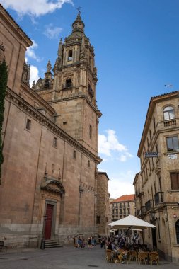 SALAMANCA, SPAIN - 3 Temmuz 2024: Salamanca İspanya 'da eski bir kasaba caddesi İglesia La Clereca Katolik Kilisesi' nin Salamanca 'daki kulelerinin manzarası ile kasabada yürüyen insanlar