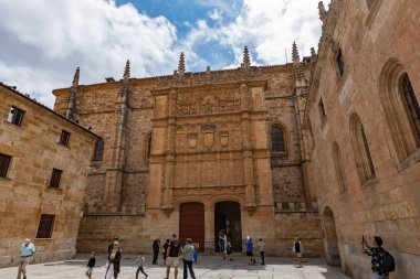 SALAMANCA, İspanya - 3 Temmuz 2024: Turistler, Avrupa 'nın en eski üniversitelerinden biri olan İspanya' nın Salamanca Üniversitesi 'nin karmaşık Plateresk maskaralığına hayran kaldılar