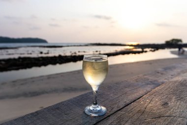 Gün batımına karşı bir kadeh beyaz şarap ve Tayland 'da deniz.