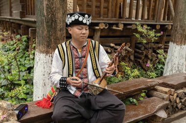 KUNMING, ÇİN - 20 Mart 2025: Yunnan 'ın Yi halkı için geleneksel bir enstrüman olan Horsehead Fiddle olarak da bilinen Touwenxian müzik aleti çalan Çinli adam