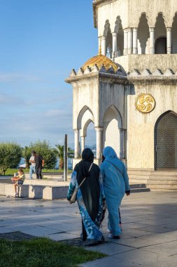 BATUMI, GEORGIA - 15 Ağustos 2024: Batumi, Georgia 'daki tarihi saat kulesinin önünde yürüyen iki Müslüman kadın