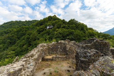Gürcistan 'ın batısındaki antik taş şato harabeleri, çarpıcı bir gökyüzü altında yemyeşil dağlar ve manzaralı vadilerle çevrili.
