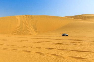 Sahilde kum tepeleri ve arabası olan bir panorama