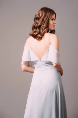 Mavi bardot gece elbisesi giymiş, dikiz manzaralı muhteşem genç bayan. Esmer kadının duygusal stüdyo portresi. Bardot 'un sırt dekoltesi yok, şık bir görünümü var. Romantik nedime yaz kıyafeti.