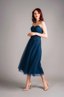 Stüdyoda dans eden güzel kızıl saçlı kadın, romantik bir portre. Koyu mavi, tatlı, yakalı bir elbise. Korsesiz klasik gece elbisesi, şenlikli kıyafet. Dokunaklı bir olay, uçan etek