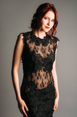 Siyahlı, şeffaf gece elbisesi. Gece kıyafetli güzel kızıl kadın, stüdyo portresi. Yüksek yakalı saf ağ ve dantel desenli elbise. Bir etkinlik için zarif bir kadın modası. Sevimli bayan.