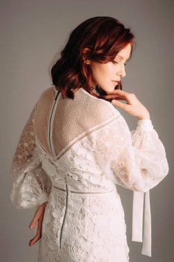 Broderie 'nin beyaz elbisesi. Kızıl kadının romantik stüdyo portresi, dikiz aynası. Yaz şenliği kıyafeti, kravatlı uzun kabarık kollar, şeffaf bir elbise. Dalgalı saç kesimli genç bayan, gelin modası.