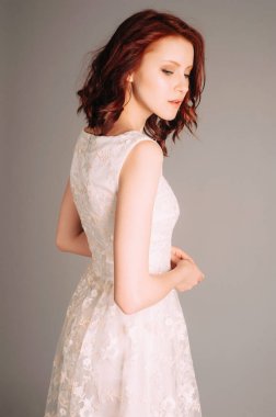 Düşünceli kızıl saçlı kadının duygusal stüdyo portresi. Nakışlı beyaz dantel elbise. Kolsuz, ince bir gece elbisesi, yaz kıyafeti. Doğal makyaj ve kıvırcık saç, dokunaklı bir şey.