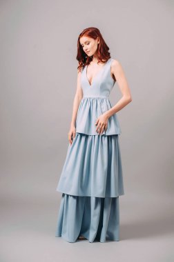 Mavi etkinlik elbisesi içindeki çekici kızıl kadın. Çağdaş nedime modası. V yaka kolsuz, etekli maksimum etekli. Bekarlığa veda partisi için modaya uygun bir görüntü. Yaz kadınsı görünümü, stüdyo resmi.