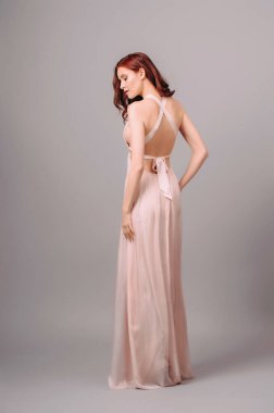 Pembe renkli transformatörsüz elbise. Baştan çıkarıcı kızıl saçlı kadın arka yay detaylarıyla maksimum gece elbisesi giyiyor. Nedimenin yaz ipek elbisesi. Kıvırcık saçlı, güzel, seksi bir bayan.