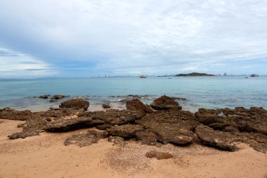 Uzak dağlar ve adalarla kayalık sahil ve denizin manzarası, mavi gökyüzü..