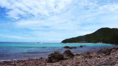 Uzak dağlar ve adalarla kayalık sahil ve denizin manzarası, mavi gökyüzü..