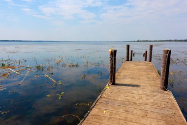 Büyük bir gölette ahşap bir iskele. Etrafında küçük kornişler var..
