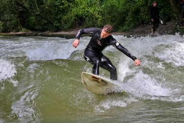 Münih, Almanya - Haziran 04, 2022: Şehir Nehrinde Sörfçü, Münih 'te Eisbach adı verilen kentsel çevrede sörf yapan insanlarla ünlüdür.