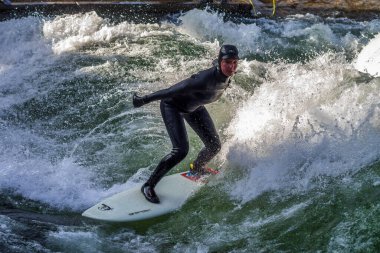 Münih, Almanya - 13 Aralık 2021: Münih şehir nehirinde kış sörfçüsü, Eisbach adı verilen kentsel çevrede sörf yapan insanlarla ünlüdür.