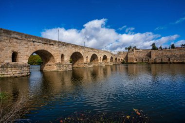 Merida, İspanya - 05 Kasım 2022: Puente Romano, Merida 'daki Roma Köprüsü. Merida 'daki Guadiana Nehri üzerinde kalan en uzun Roma köprüsü. Arka planda Alcazaba 'yı görüyoruz..