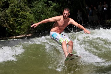 Münih, Almanya - Haziran 04, 2022: Şehir Nehrinde Sörfçü, Münih 'te Eisbach adı verilen kentsel çevrede sörf yapan insanlarla ünlüdür.