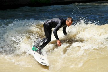 Münih, Almanya - Haziran 04, 2022: Şehir Nehrinde Sörfçü, Münih 'te Eisbach adı verilen kentsel çevrede sörf yapan insanlarla ünlüdür.