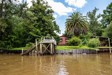 Boat tour on the Parana Delta, Tigre, Buenos Aires, Argentina. Lush vegetation, palm trees, construction site of modern brick house. Lujan River delta system bringing water to Rio de la Plata.