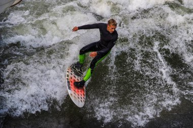 Münih, Almanya - 13 Ekim 2022: Münih şehir nehrinde sörfçü, Eisbach adı verilen kentsel çevrede sörf yapan insanlarla ünlüdür.
