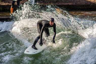 Münih, Almanya - 13 Aralık 2022: Şehir Nehrinde Kış Sörfçüsü, Münih şehir çevresinde Eisbach adı verilen sörf yapan insanlarla ünlüdür.