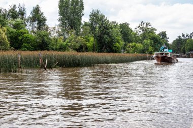 Boat tour on the Parana Delta, Tigre, Buenos Aires, Argentina. Lush vegetation, palm trees, construction site of modern brick house. Lujan River delta system bringing water to Rio de la Plata.