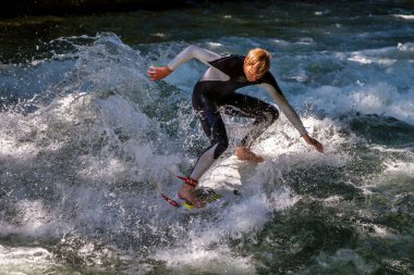 Münih, Almanya - Haziran 04, 2023: Şehir Nehrinde Sörfçü, Münih 'te Eisbach adı verilen kentsel çevrede sörf yapan insanlarla ünlüdür.