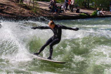 Münih, Almanya - Haziran 04, 2024: Şehir Nehrinde Sörfçü, Münih 'te Eisbach adı verilen kentsel çevrede sörf yapan insanlarla ünlüdür.